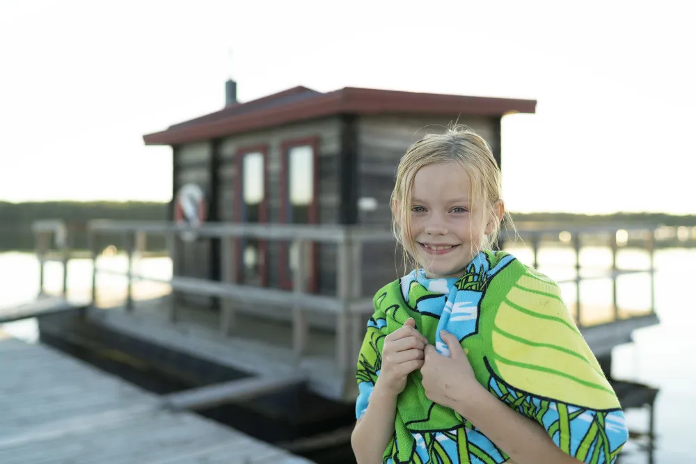 Ett barn i badrock vid bastu i Stenö