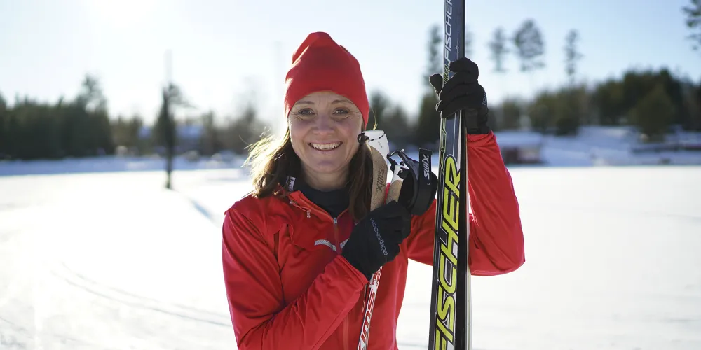 En glad kvinna som ska åka längdskidor