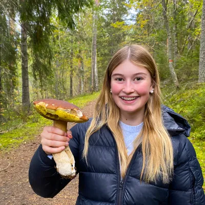 En glad tjej som håller upp en svamp på vandringen