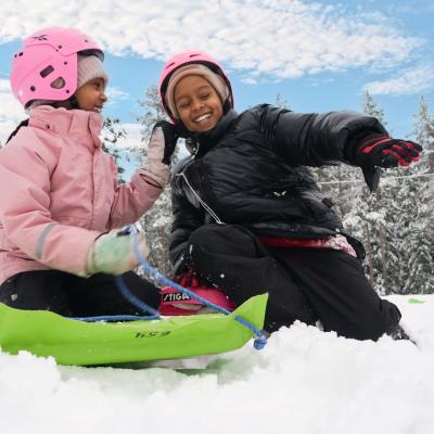 Barn som leker i snön och åker pulka