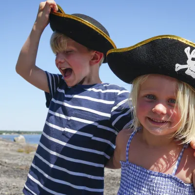 Två glada barn bär pirathatt i skärgården