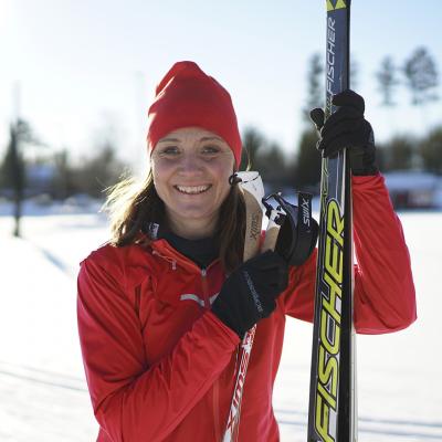 En kvinna med längdskidor i soligt vinterlandskap