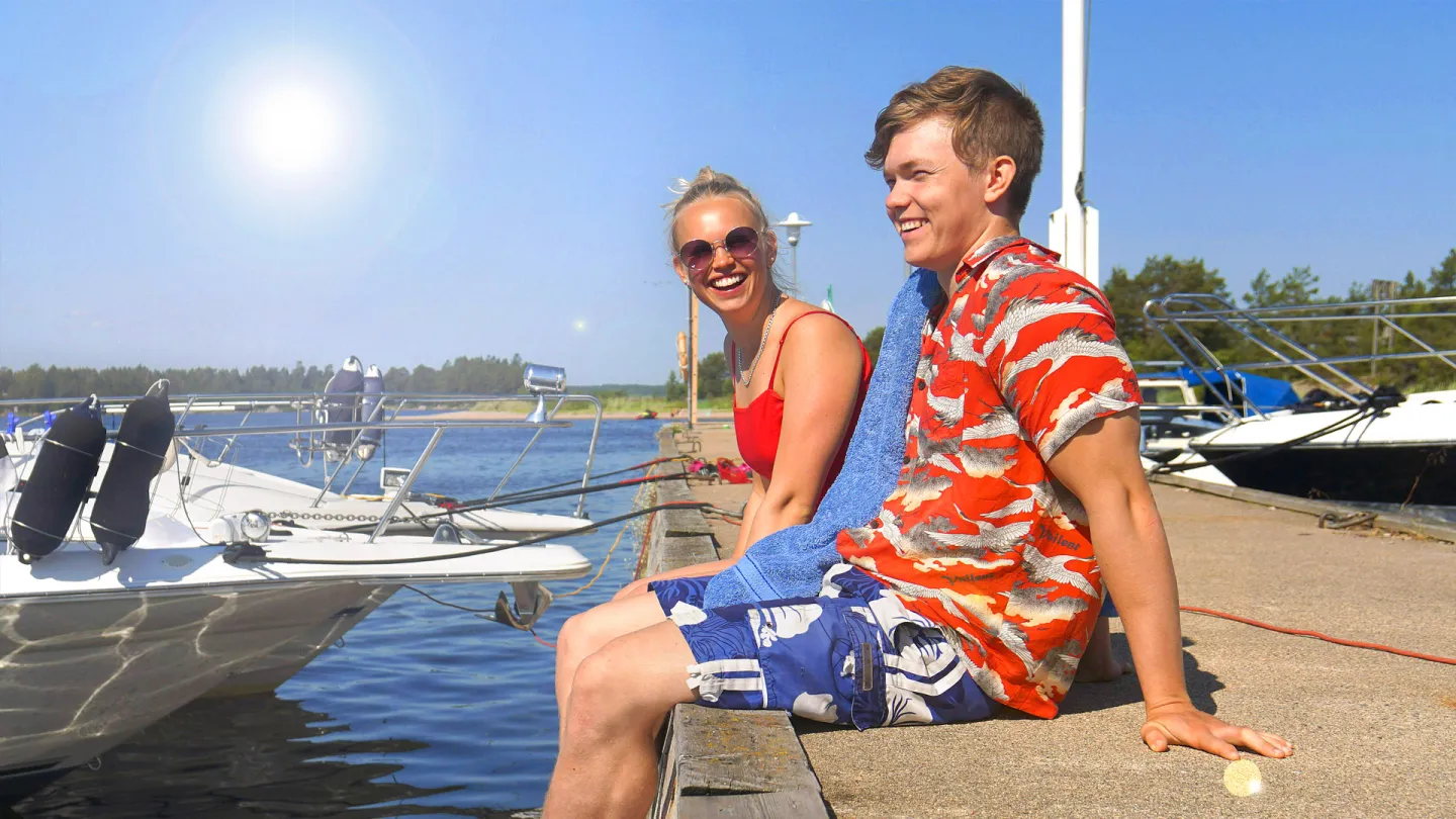 Ett par som sitter på kajen vid Enskärorens gästhamn