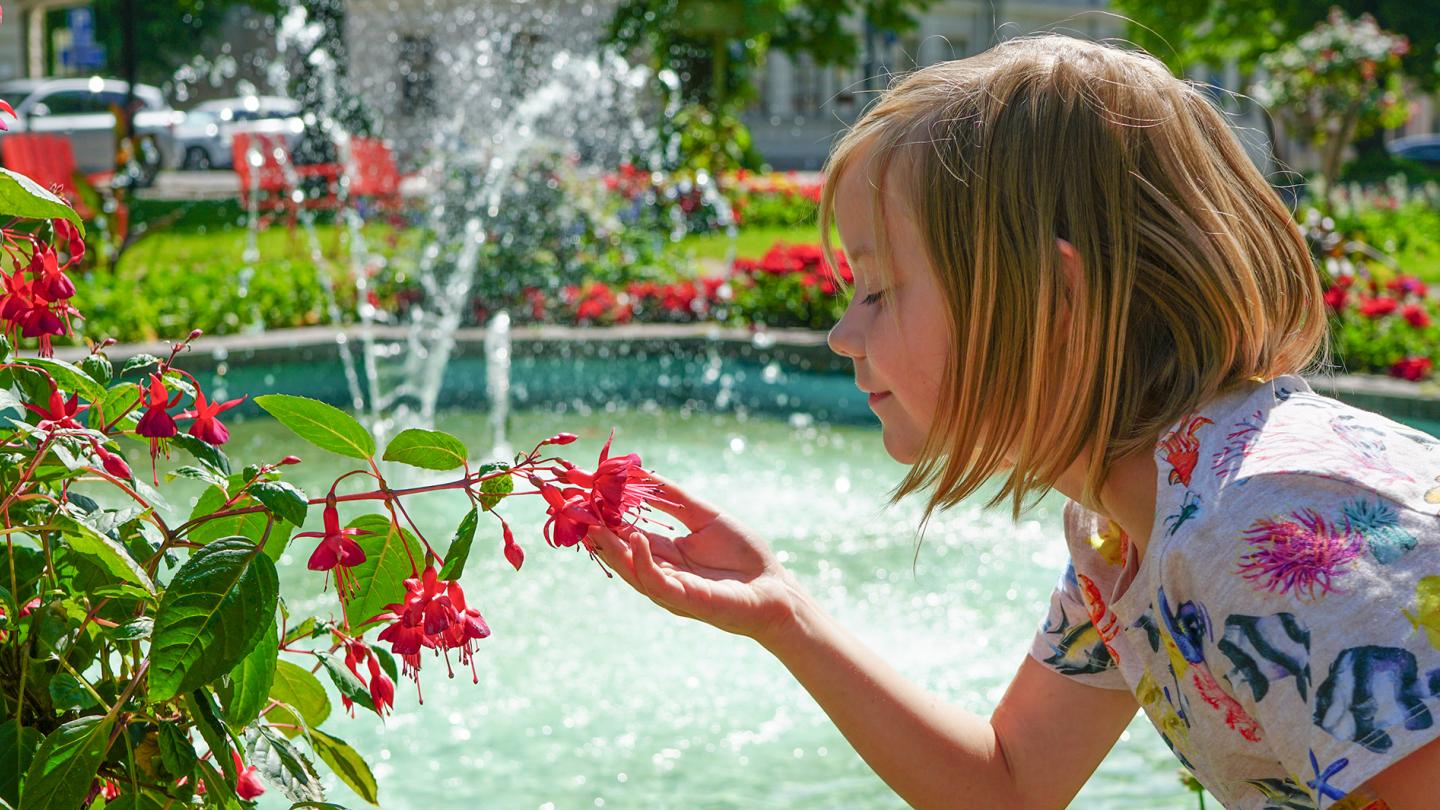 Ett barn som luktar på en blomma i en park
